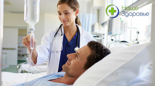Врач стоит около кровати пациента, который лежит под капельницей